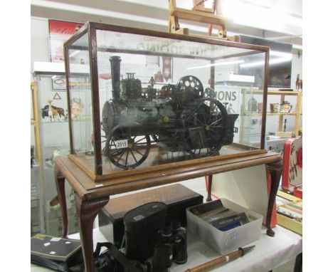 A handbuilt clockwork traction engine in custom built case on stand.  Cabinet is 78cm long x 46.5cm tall x 37cm wide.The spri