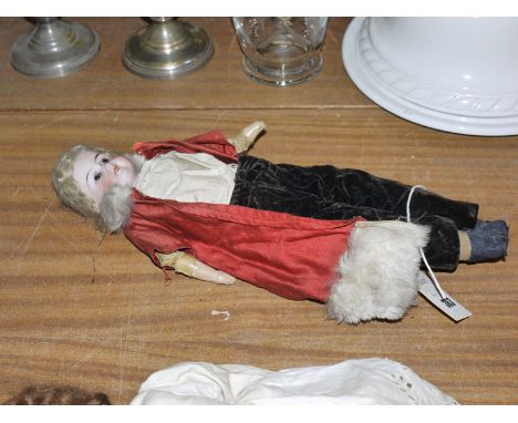 An antique German bisque head doll, with rolling eyes, open mouth, blond hair, wearing brown trousers, cream bodice and a red