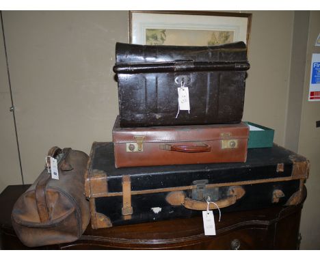 A suitcase with leather trimmings; an attache case; a small tin trunk; and a leather Gladstone bag.
