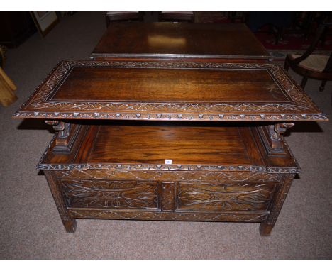 An early 20th Century stained and carved oak monk's bench, the hinged top on lion supports, the seat with hinged cover, panel