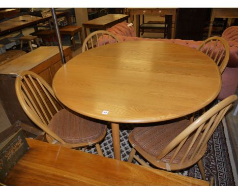 An Ercol oval gateleg dining table in light elm; together with four matching solid seat dining chairs with spindle backs, rai