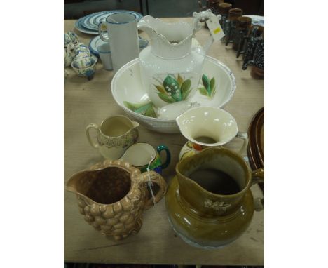 A three-piece Victorian jug and bowl set decorated lily of the valley; a stoneware glaze jug with raised hunting scene decora