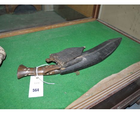 A kukri knife in scabbard; with smaller knife and fork.