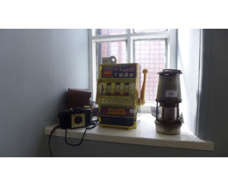 A collection of retro cameras  and a miniature slot machine and a miner's lamp (a lot)  