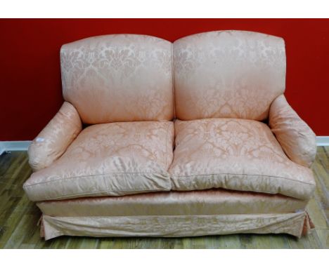 A two seater sofa having padded back supports and arms upholstered in a rose floral fabric raised on squared supports and cas