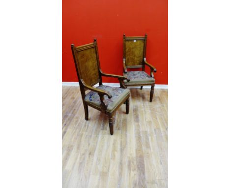 A pair of 19th Century oak hall chairs, having a moulded top rail over panel back & carved scroll work arms above stuff over 