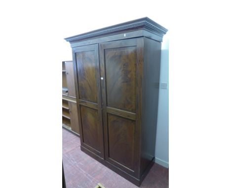 A 19th Century mahogany wardrobe having a moulded cornice over twin panel doors enclosing a fitted interior, raised on plinth