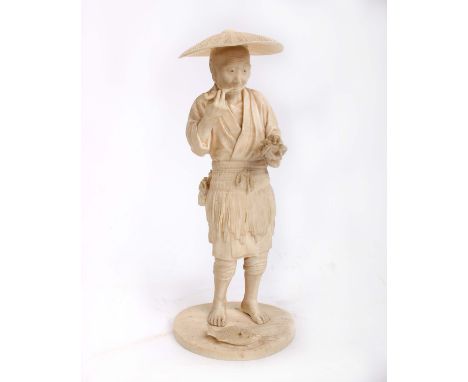 A Japanese carved ivory figure of a fisherman, standing smoking a pipe holding a lobster in his left hand, on an oval base, s