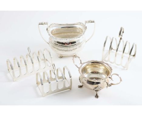 A MODERN TWO-HANDLED SUGAR BOWL on four paw feet, a two-handled sugar bowl on four button feet and three small toast racks, m