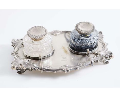 AN EDWARDIAN INKSTAND with a decorative border, four scroll pen rests and two mounted cut-glass ink bottles, crested, by Jame