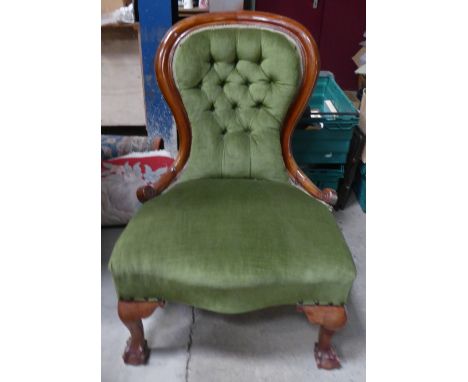 A Victorian mahogany frame spoon back Nursing Chair with button upholstered back and serpentine fronted seat, on claw and bal