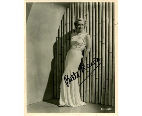 DAVIS BETTE: (1908-1989) American actress, Academy Award winner. Signed 8 x 10 photograph of the young Davis standing in an e