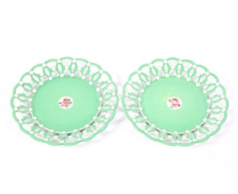 A pair of Spode plates, with reticulated borders, in a green glaze with white detailing, and painted central floral bouquet, 