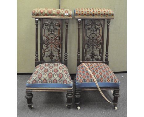 A pair of Victorian prayer chairs, each back carved in ornate openwork surrounding a central cross, with tapestry upholstery,