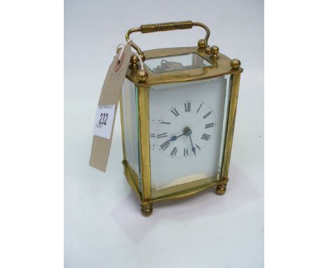 A French brass carriage timepiece with a white enamel dial and Roman numerals.