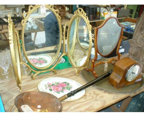 A Gilt framed triple mirror with a ribbon tied crest, a shield shaped mahogany framed mirror, a circular brass plaque, copper