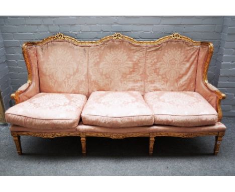 A Louis XVI style gilt framed sofa, with ribbon tied triple hump back, on fluted square supports, 198cm wide x 105cm high.