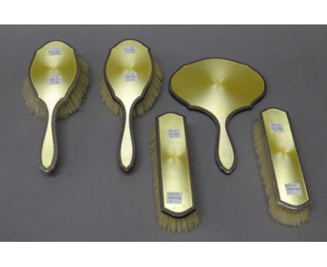 A lady's silver and yellow enamel mounted five piece part dressing set, comprising; a hand mirror, Birmingham 1922, a pair of