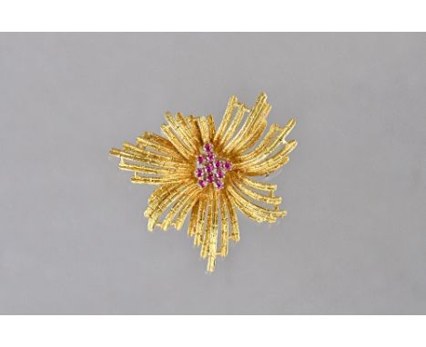 An 18ct gold and ruby brooch, in a stylized starburst design, with a textured finish, claw set with a cluster of ciruclar cut