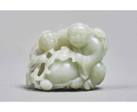 A Chinese celadon jade group of the Hehe Erxian, Qing Dynasty, the smiling twins carved seated with a bat and branches of fru