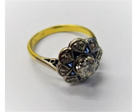 A gold, diamond and synthetic sapphire cluster ring, claw set with the principal circular cut diamond in a surround of eight 