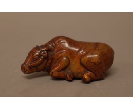 A Japanese wood netsuke of a recumbent ox, probably 19th century, carved lying with head turned slightly, unsigned, 6.5cm. le