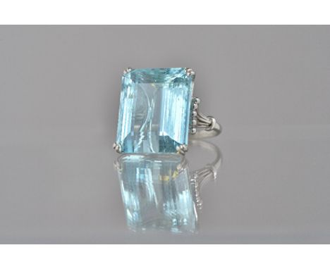 An aquamarine single stone ring, claw set with a large cut cornered rectangular step cut aquamarine, between beaded wirework 