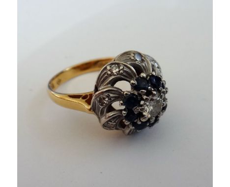 An 18ct gold, diamond and sapphire cluster ring, claw set with the principal circular cut diamond at the centre, in a surroun