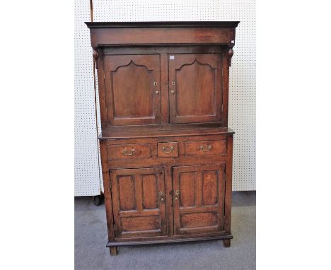 A mid-18th century oak court cupboard, the canopy top over a pair of shaped panel doors, three drawers and a further pair of 
