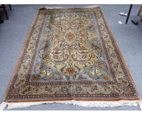A Ghom rug, Persian, the beige field with a small central rosette, floral sprays, grey spandrels with hunting lions and tiger
