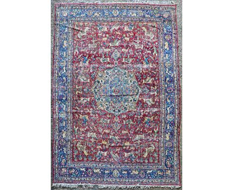 A Tehran carpet Persian, the madder field with a bold ivory and pale indigo medallion, allover with hunting scenes with vario