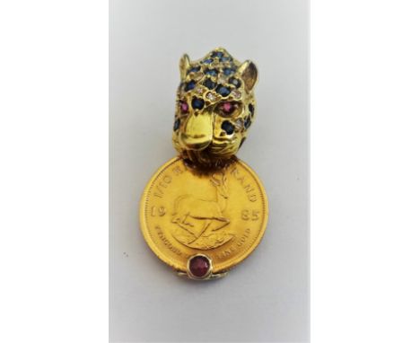 A gold, diamond, sapphire and ruby pendant, designed as a leopard's head, fitted with a gold mounted South Africa one tenth o