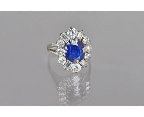 A sapphire and diamond oval cluster ring, claw set with the oval cut sapphire in a surround of eight circular cut diamonds an