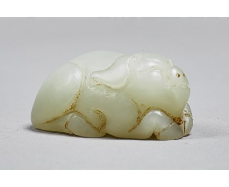 A Chinese celadon jade figure of a pig, Qing Dynasty, carved in recumbent pose with front trotters tucked under its chin, 5cm