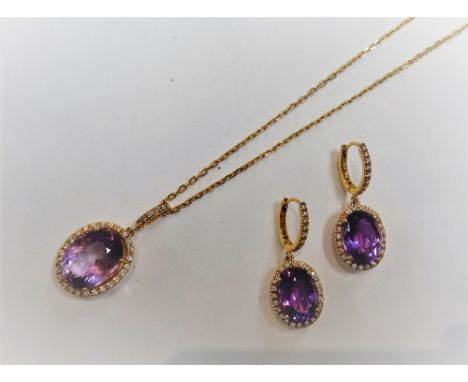 A gold, amethyst and diamond oval pendant, claw set with the oval cut amethyst at the centre, in an openwork surround, set wi