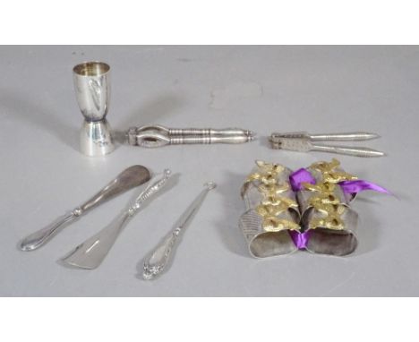 A group of silver plated items to include napkin rings, two pairs of nutcrackers, two silver plated shoe horns, a shot measur