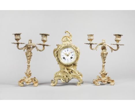 A French gilt brass clock garnitureIn the Louis XV style, circa 1875The clock of shaped outline with  3 1/2 in. circular whit