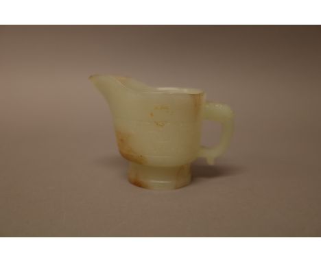 A Chinese pale celadon jade libation cup, carved with a band of archaic scrolls, 7cm. high.