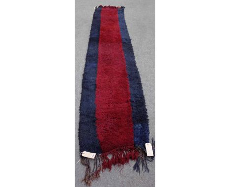 An Uzbek runner, the plain madder field bordered by plain indigo panel, 370cm x 70cm. 