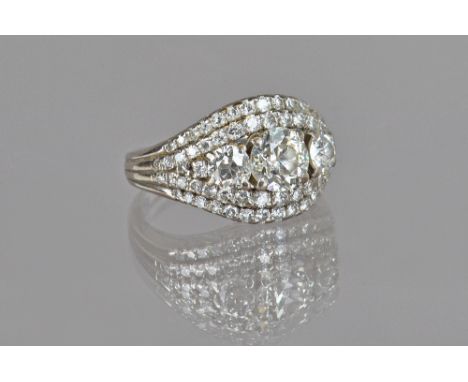 A diamond ring, claw set with the three principal cushion shaped diamonds to the centre, between circular cut diamond set two