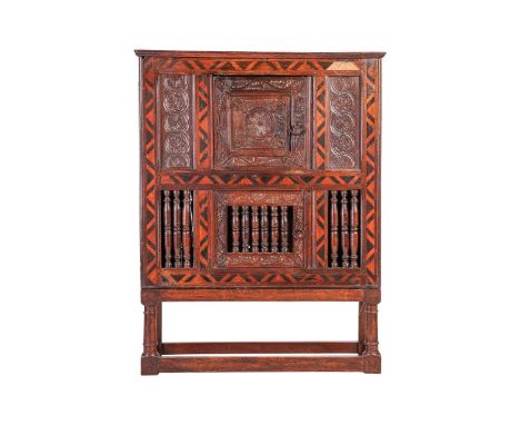 A part 17th century oak Dole cupboard, with a carved single door above a lower section of a central door with spindle panels 