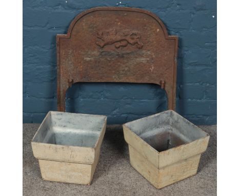 A cast iron fireplace back with lion decoration along with a pair of cast iron drain hoppers.  