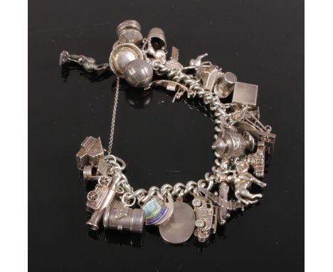 A Silver and white metal charm bracelet. with 33 charms, key, aeroplane, fire engine, top hat, stork, post box with postman i