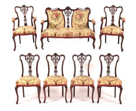 An Edwardian carved&nbsp;mahogany salon suite, comprising a settee, two arm chairs, and four single chairs, with elaborately 