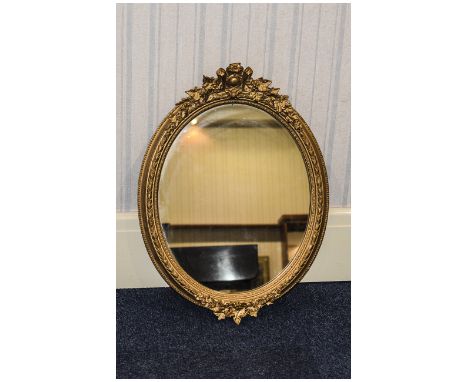 Gilt Framed Mirror Oval mirror with gilt surround featuring fruit, foliage and vine design, good condition.