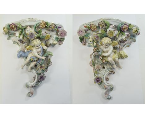 Volkstedt Pair of Cherub Wall Brackets, each showing a seated cherub amongst applied polychrome flowers, against a cornucopia