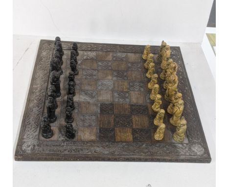 A mid/late 20th century Oriental wooden carved chessboard, 60.5cm x 60.5cm, together with resin cast Chinese chess piecesLoca