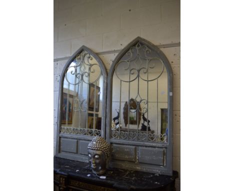 A pair of arch shaped garden mirrors with ornate wrought iron decoration.