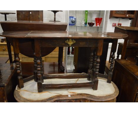 An oak single drawer side table with a drop flap to each end on turned gate-leg supports.