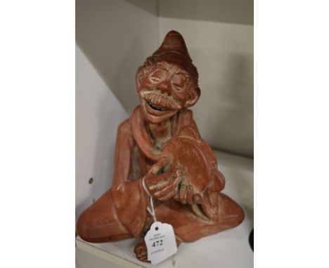 Moulded terracotta figure of a man playing a tambourine.